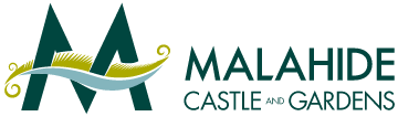 Logo for Malahide Castle and Gardens featuring two large, stylized dark green "M"s with a yellow and white decorative element resembling a medieval banner draped across them. The text "Malahide Castle and Gardens" is in dark green to the right of the emblem.